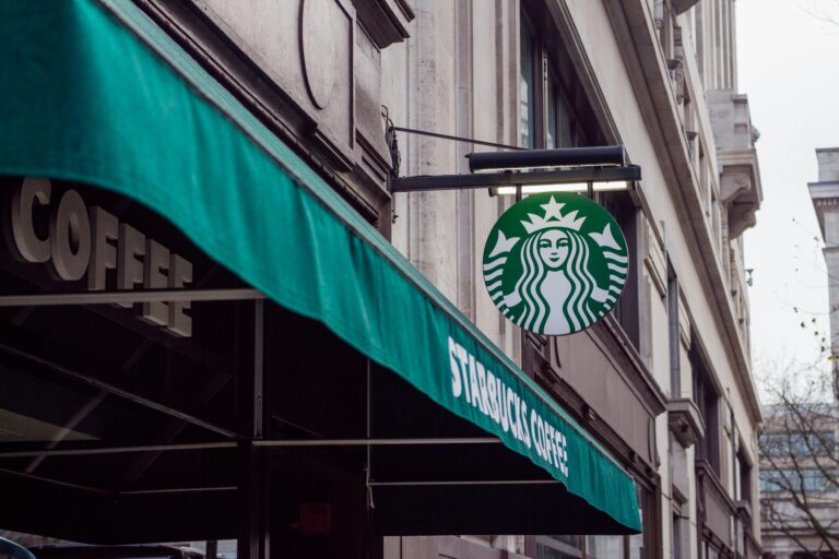 Exterior view of a Starbucks coffee shop in a city setting, featuring signage and awning.