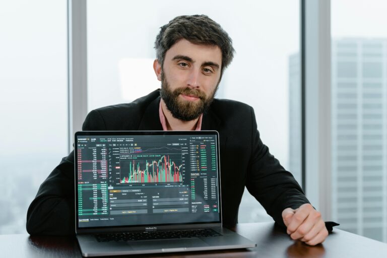 Businessman in office analyzing stock market trading data on a laptop screen.