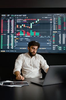 Focused man working on cryptocurrency trading with charts displayed in office.