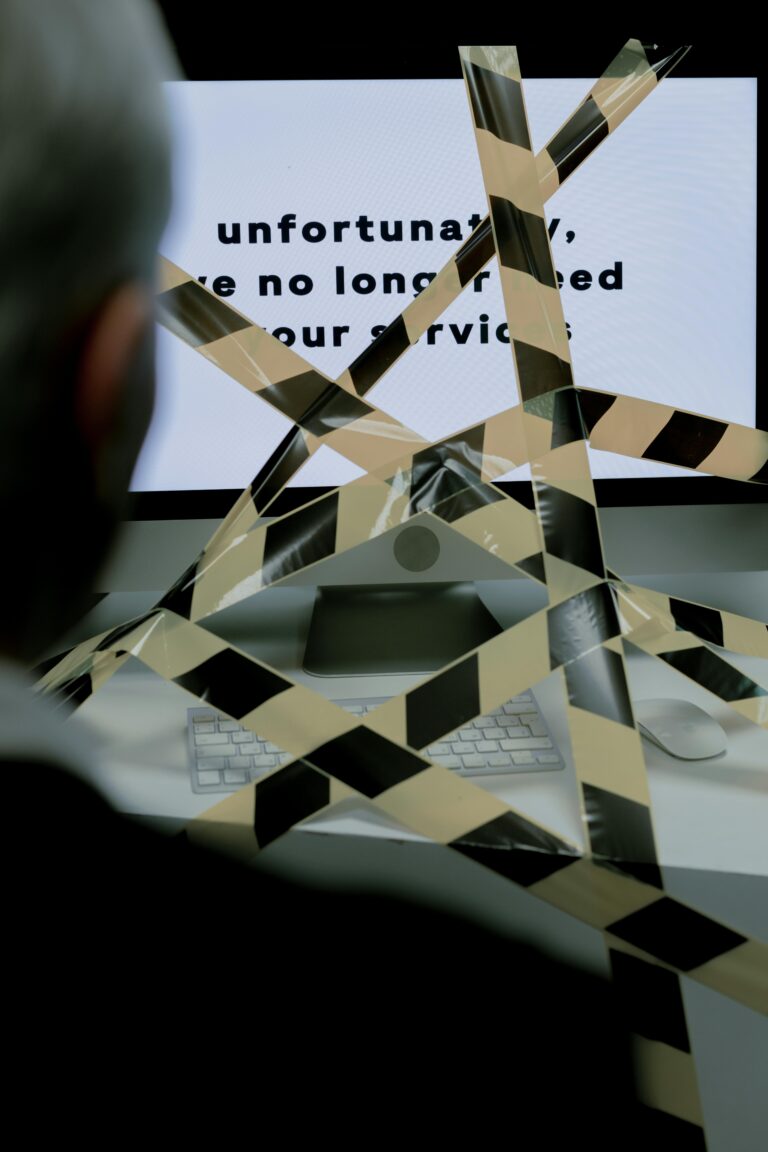 A man views a rejection message on a computer screen blocked by caution tape, symbolizing unemployment.